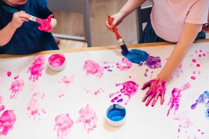 Children finger painting with colorful hands, symbolizing creativity and neurodivergent expression in ADHD.