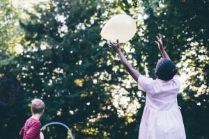 School-aged girl reaching for a balloon on a sunny day, symbolizing freedom and flexibility during summer ADHD medication breaks