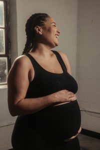 Pregnant woman with ADHD writing in a journal as part of her mental health self-care routine.